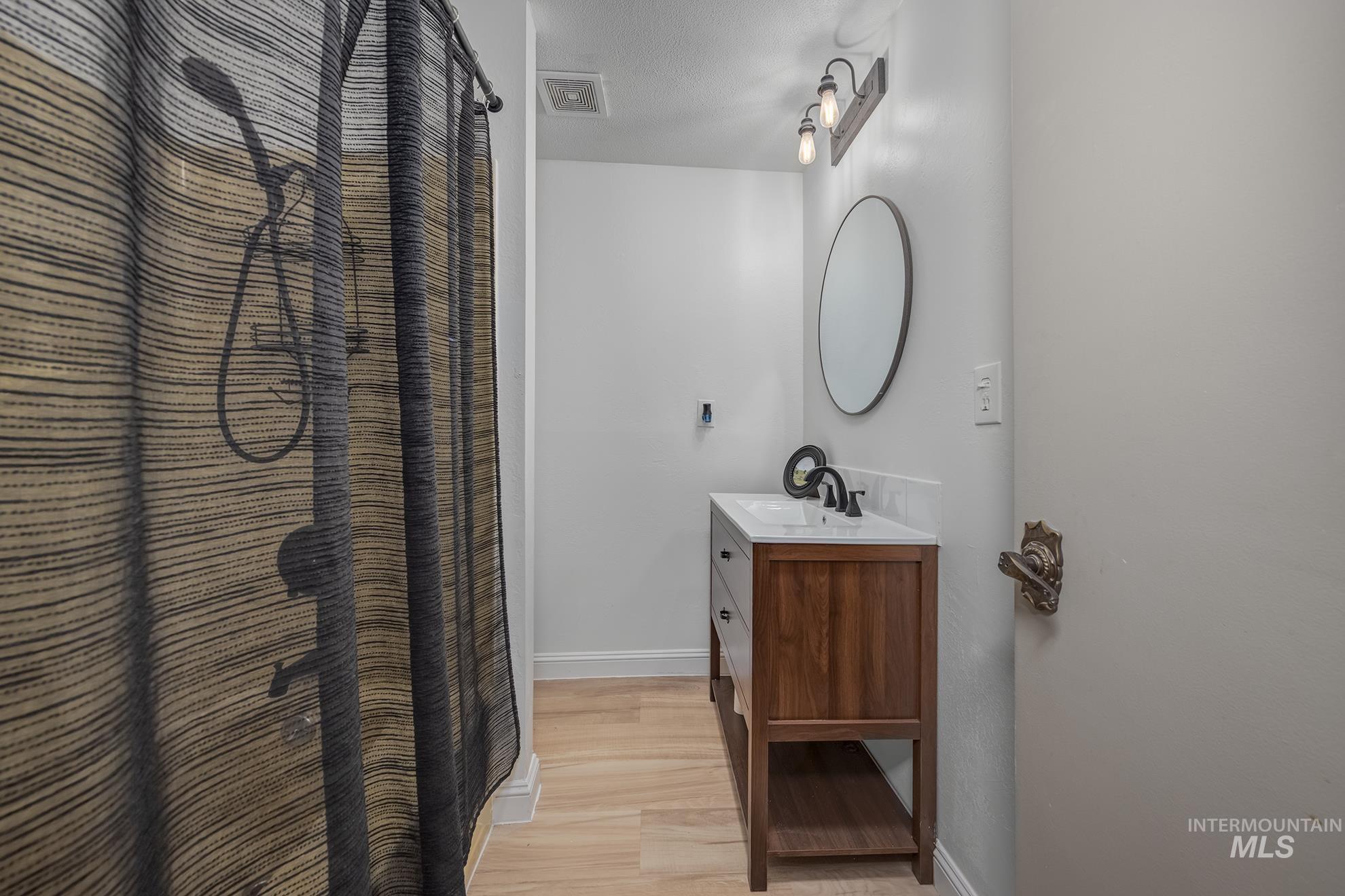 61 Southwest 4th Street Ontario, OR 97914 - Photo 24 of 42 Bathroom featuring a wood-finish vanity with a white countertop, an oval mirror, and a three-light fixture