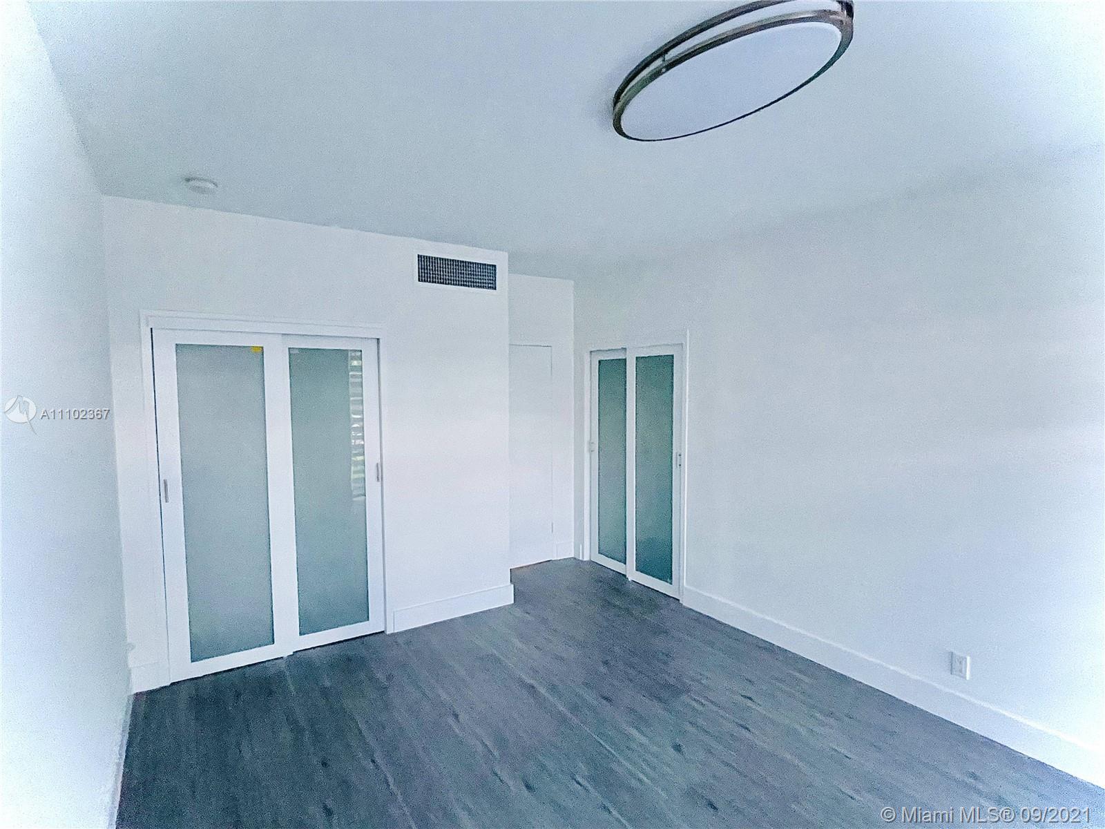 880 Northeast 69th Street, Unit 1D Miami, FL 33138 - Photo 10 of 15 an empty room with wooden floor and windows