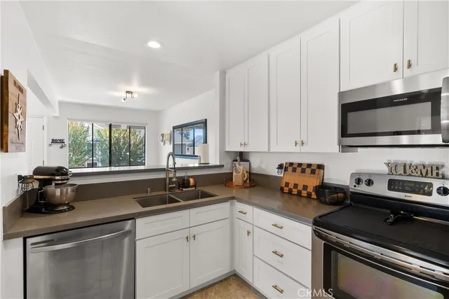 a kitchen with stainless steel appliances a sink a stove a microwave cabinets and a window