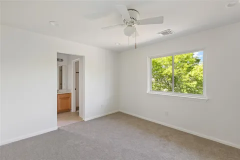 a view of empty room with window and ceiling fan