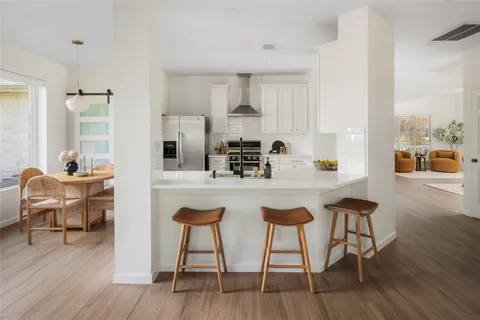 a kitchen with stainless steel appliances granite countertop a table chairs stove and wooden floor