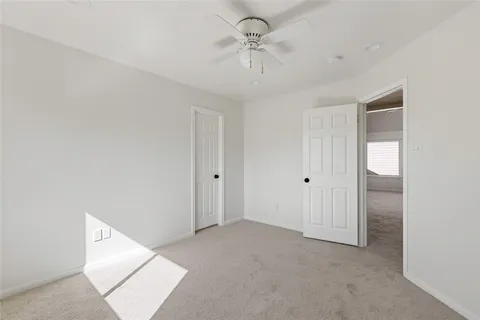 an empty room with windows and chandelier fan