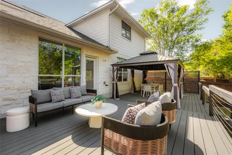a view of a patio with couches and a table and chairs with wooden floor and fence