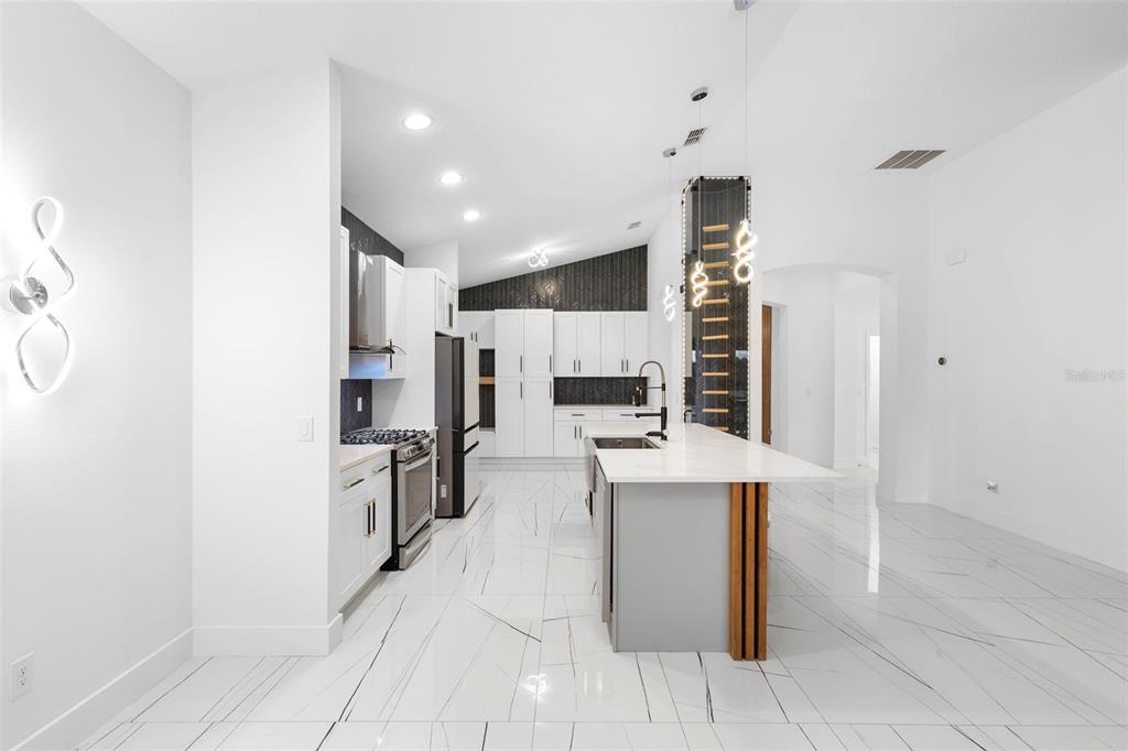 2342 Kaley Ridge Road Clermont, FL 34715 - Photo 19 of 54 a kitchen with stainless steel appliances kitchen island granite countertop a refrigerator and a stove top oven
