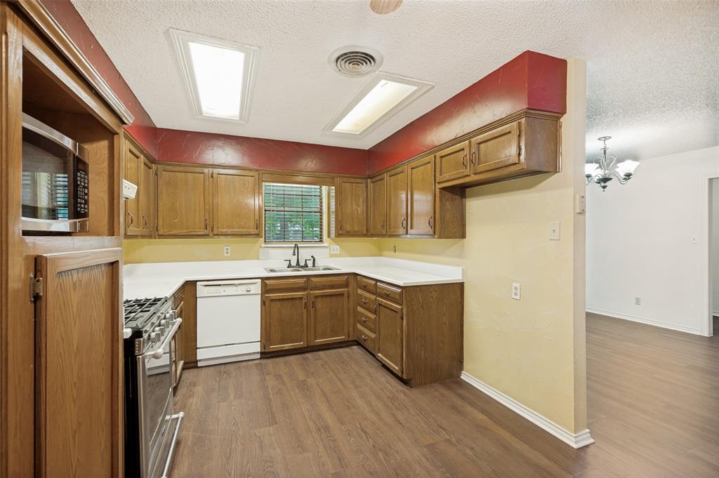 508 South Pedigo Street Pilot Point, TX 76258 - Photo 9 of 26 Kitchen featuring wood-finish flooring, wood cabinetry, white marble countertops, and a suite of appliances including a dishwasher and range