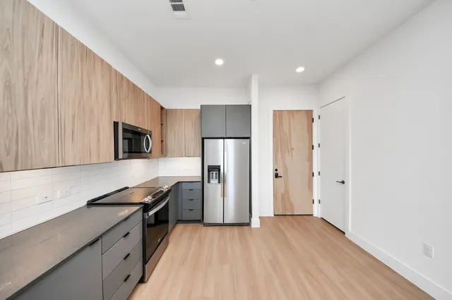 a view of a kitchen with a refrigerator and wooden floor