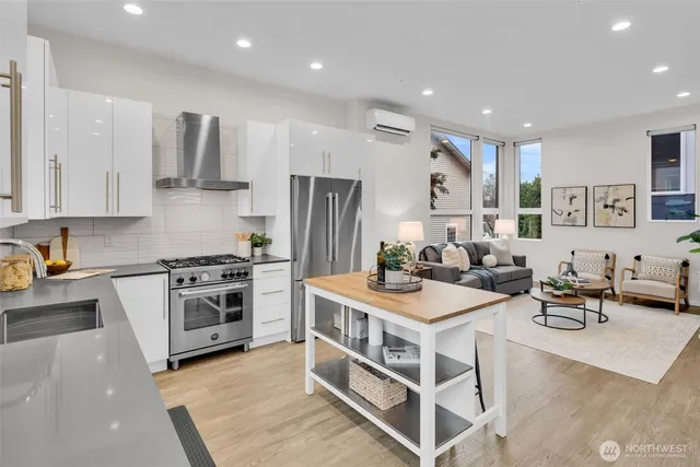 a kitchen with stainless steel appliances granite countertop a stove oven and a refrigerator a sink with white cabinets