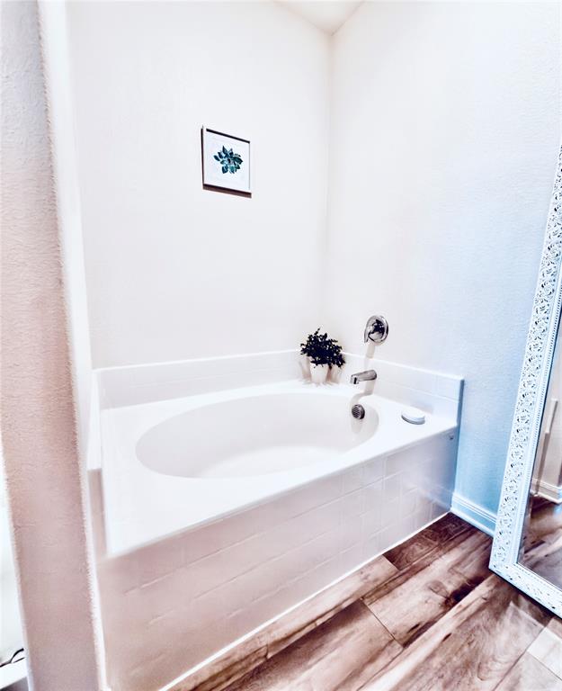 196 Cattlemans Crk Road West Newark, TX 76071 - Photo 14 of 31 Soaking tub with a white tile surround, chrome fixtures, and wood-finish flooring