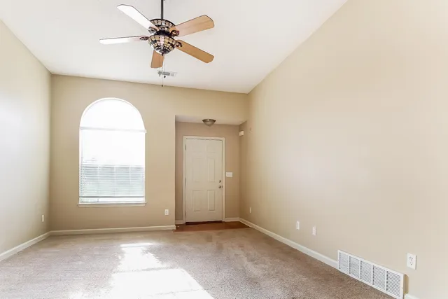 an empty room with windows and fan