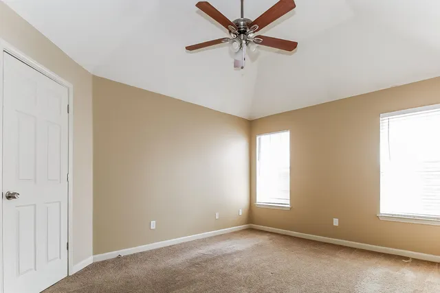 a view of a big room with windows and chandelier fan