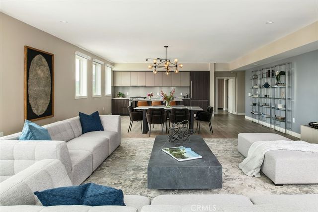 a living room with furniture chandelier and a dining table with kitchen view
