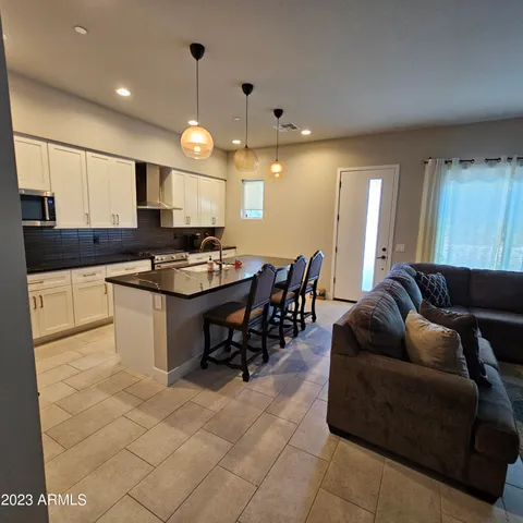 a kitchen with stainless steel appliances kitchen island granite countertop a sink a counter top space and a view of living room
