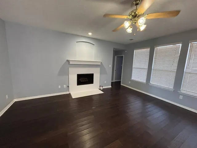 an empty room with wooden floor fireplace and windows