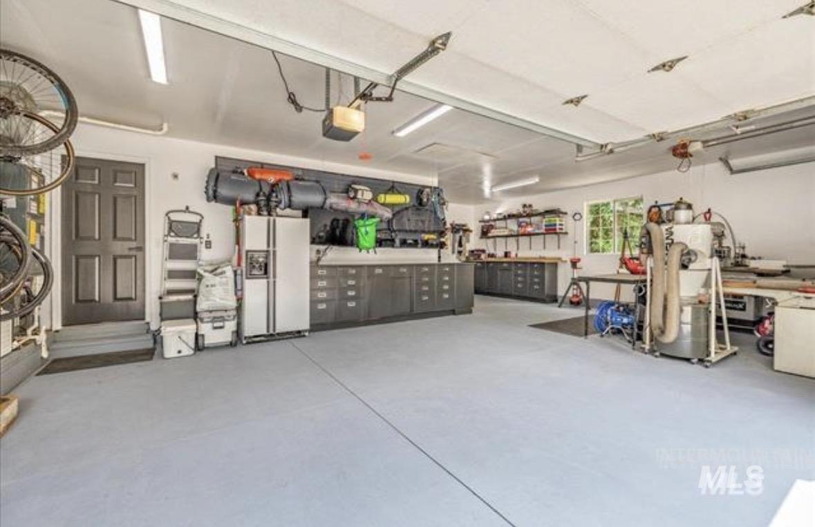 6600 East Victory Road Nampa, ID 83687 - Photo 13 of 19 Expansive garage featuring a painted concrete floor, extensive built-in cabinetry, workbench areas, and ample overhead lighting