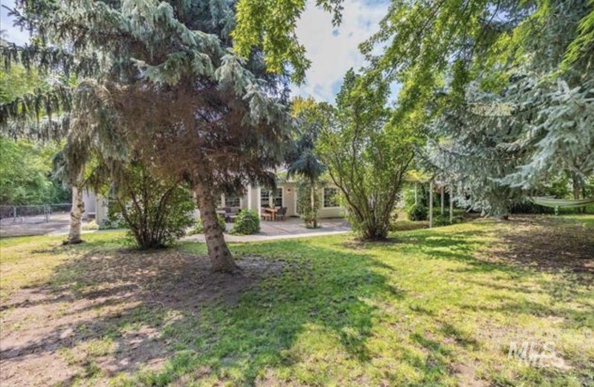 6600 East Victory Road Nampa, ID 83687 - Photo 19 of 19 Expansive rear yard featuring a manicured lawn, mature trees, and a paved patio with a pergola