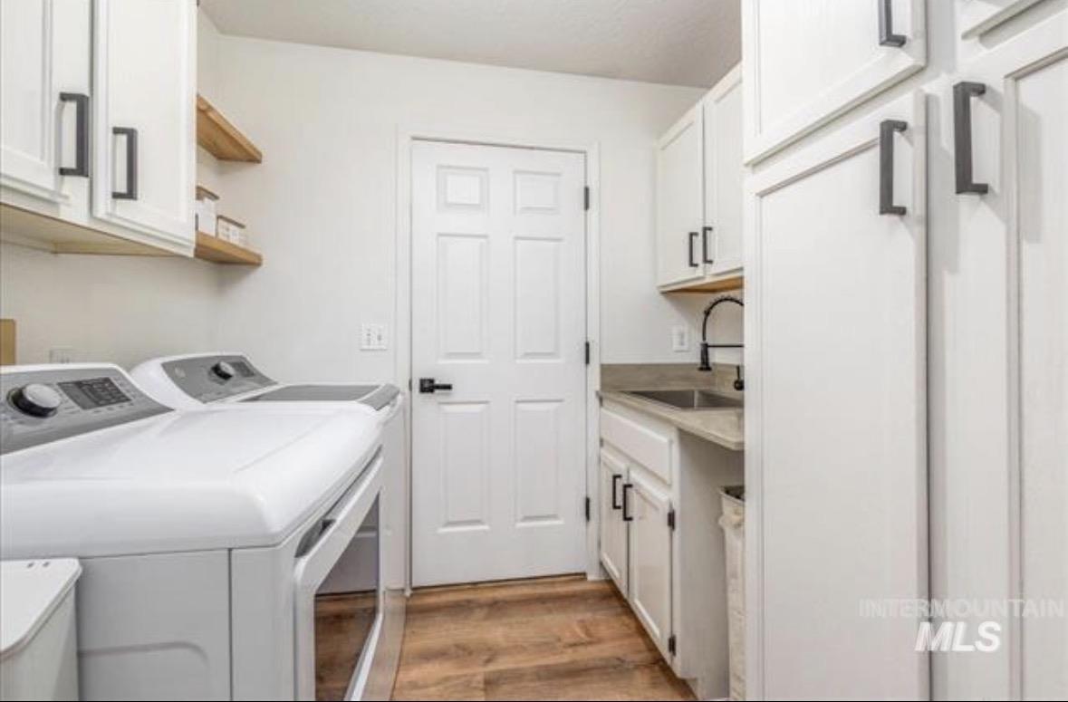 6600 East Victory Road Nampa, ID 83687 - Photo 4 of 19 Laundry room featuring white cabinetry, wood-finish flooring, a utility sink with a matte black faucet, and open shelving