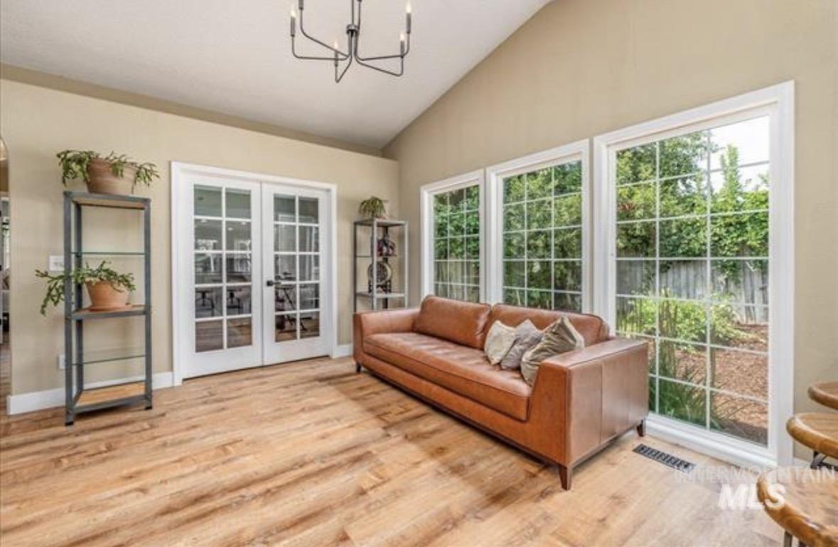 6600 East Victory Road Nampa, ID 83687 - Photo 6 of 19 Vaulted ceiling with a contemporary chandelier, multiple large pane windows, wood-finish flooring, and white frame French doors