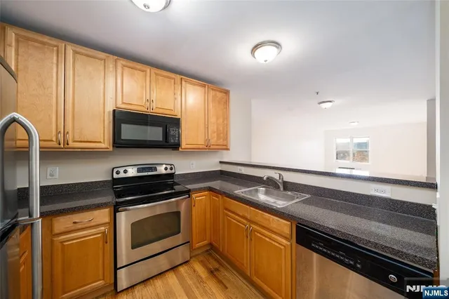 a kitchen with granite countertop a sink cabinets and stainless steel appliances