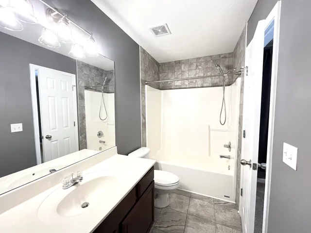 a bathroom with a bathtub shower sink vanity and toilet