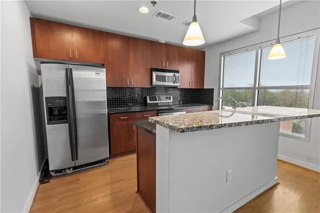 a kitchen with stainless steel appliances granite countertop a refrigerator a stove a sink and a microwave