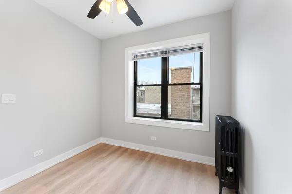 an empty room with a window and a ceiling fan