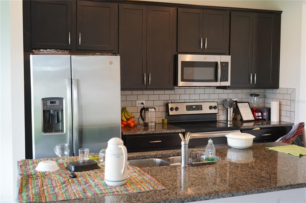 2850 Wadeview Loop St. Cloud, FL 34769 - Photo 5 of 17 a kitchen with stainless steel appliances granite countertop a refrigerator a stove top oven and a sink