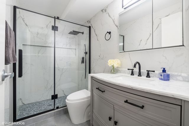 a bathroom with a granite countertop sink a toilet and shower