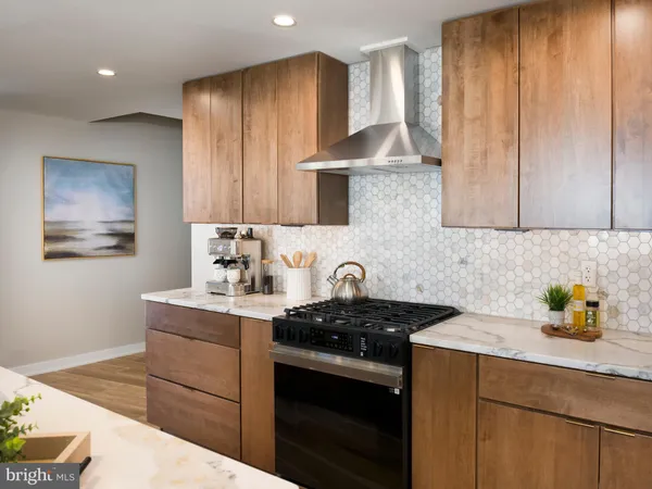 a kitchen with stainless steel appliances granite countertop a refrigerator a stove a sink dishwasher and a dining table with wooden floor