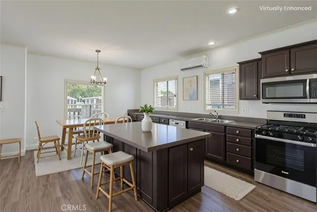 a kitchen with stainless steel appliances granite countertop a stove a sink dishwasher a dining table and chairs with wooden floor