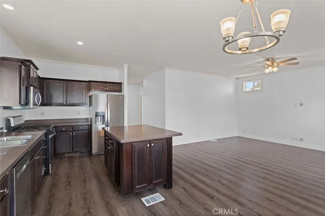 a kitchen with stainless steel appliances a stove a sink dishwasher and a refrigerator with wooden floor