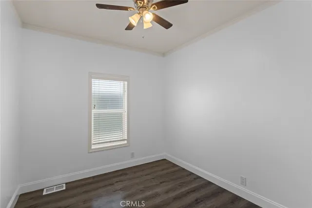 an empty room with wooden floor chandelier fan and windows