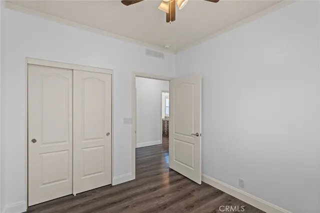 an empty room with wooden floor cabinet and ceiling fan