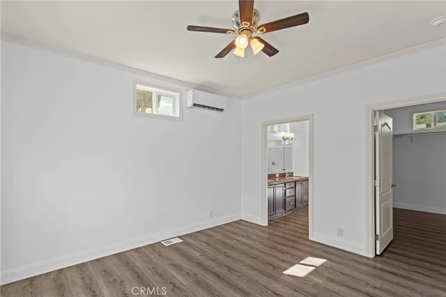 an empty room with wooden floor chandelier fan and windows