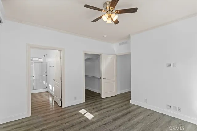 an empty room with wooden floor and ceiling fan