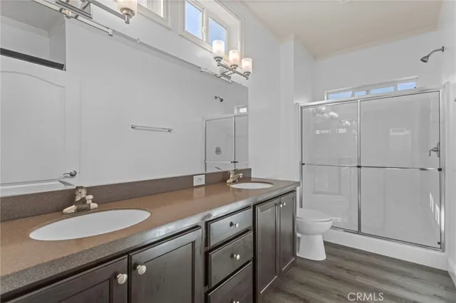 a bathroom with a granite countertop sink a toilet a mirror and shower