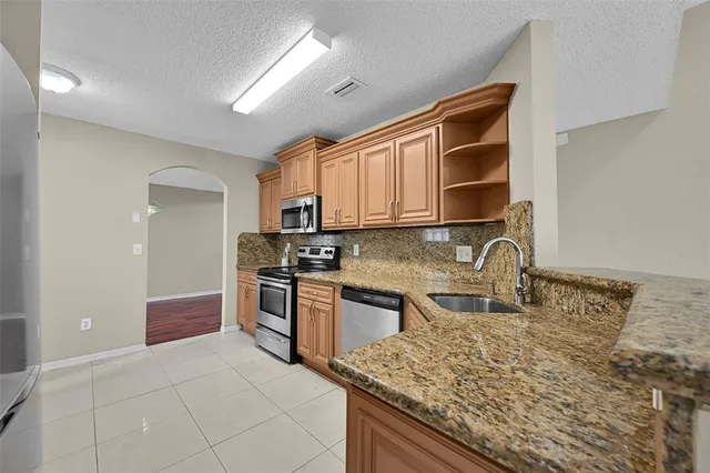 a kitchen with stainless steel appliances granite countertop a stove sink and cabinets