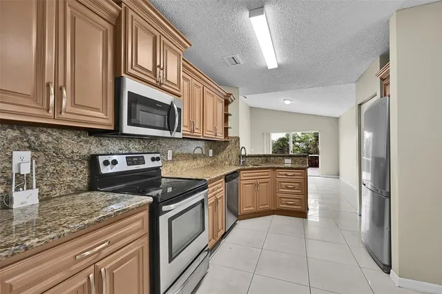 a kitchen with stainless steel appliances granite countertop a refrigerator and a stove top oven