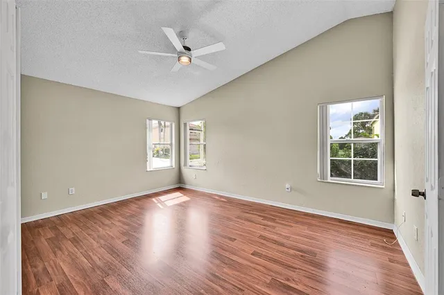 a view of empty room with wooden floor and fan