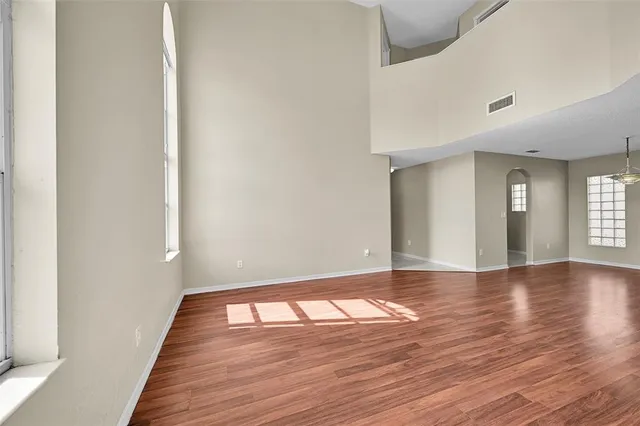 an empty room with wooden floor and windows