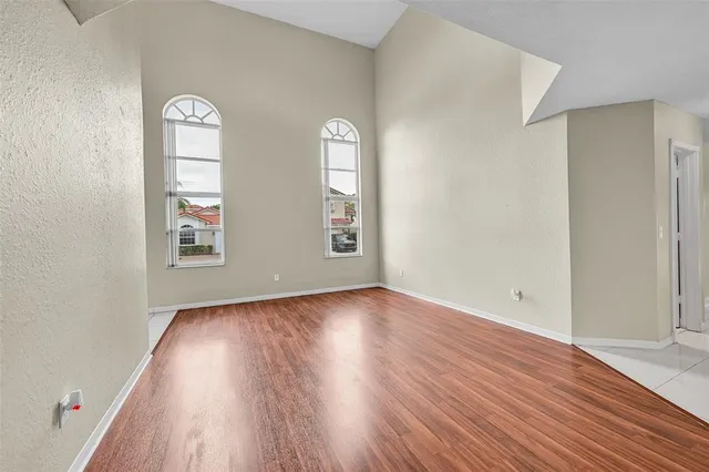 an empty room with wooden floor closet and windows