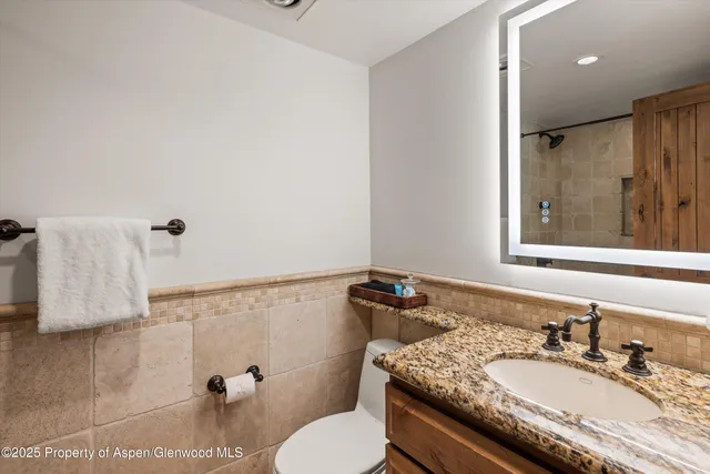 a bathroom with a granite countertop sink a mirror and a toilet