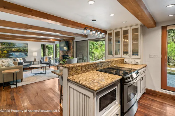 a kitchen with a stove and a view of living room