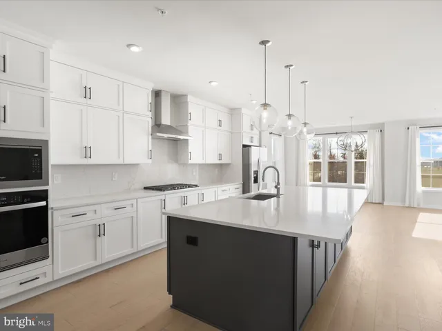 a kitchen with stainless steel appliances granite countertop a stove a sink a oven and white cabinets with wooden floor