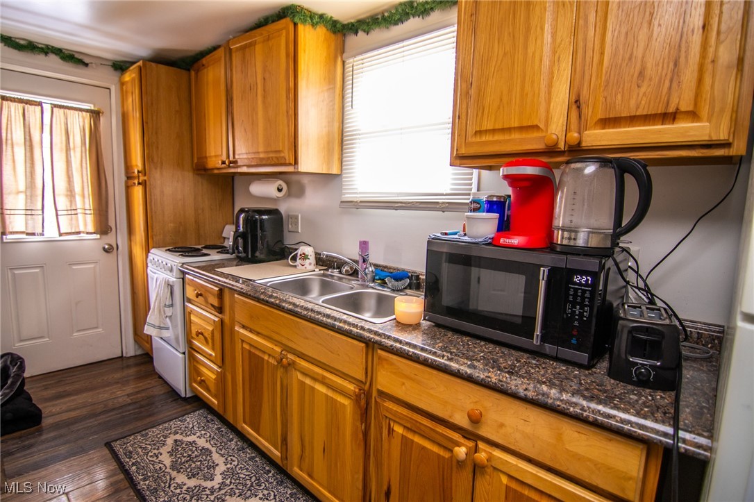 55577 National Road Bridgeport, OH 43912 - Photo 13 of 17 Kitchen featuring dark wood-style floors, brown cabinetry, a sink, and white electric range oven