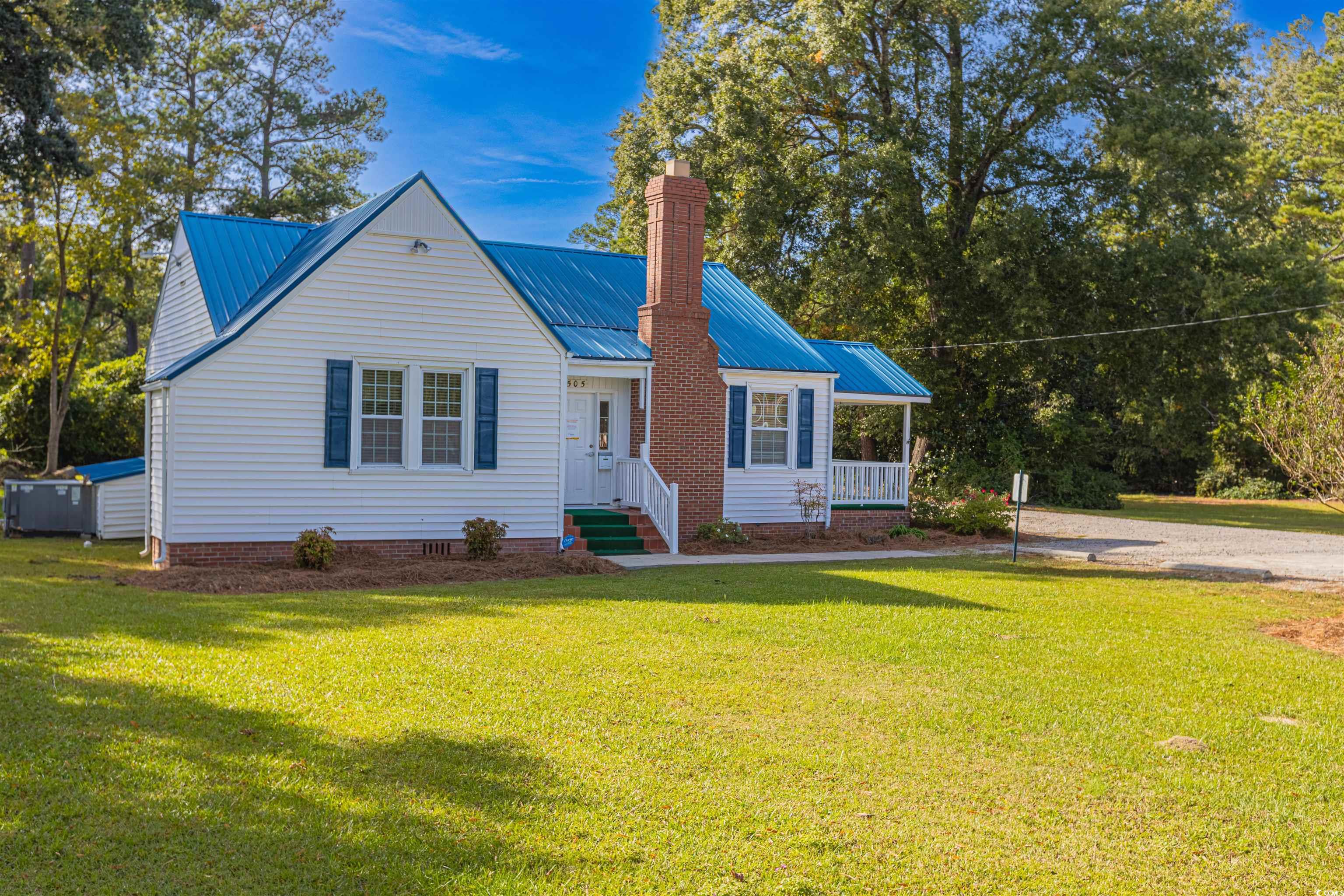 Bungalow-style house with a front lawn, a metal roof, a chimney, covered porch, and crawl space