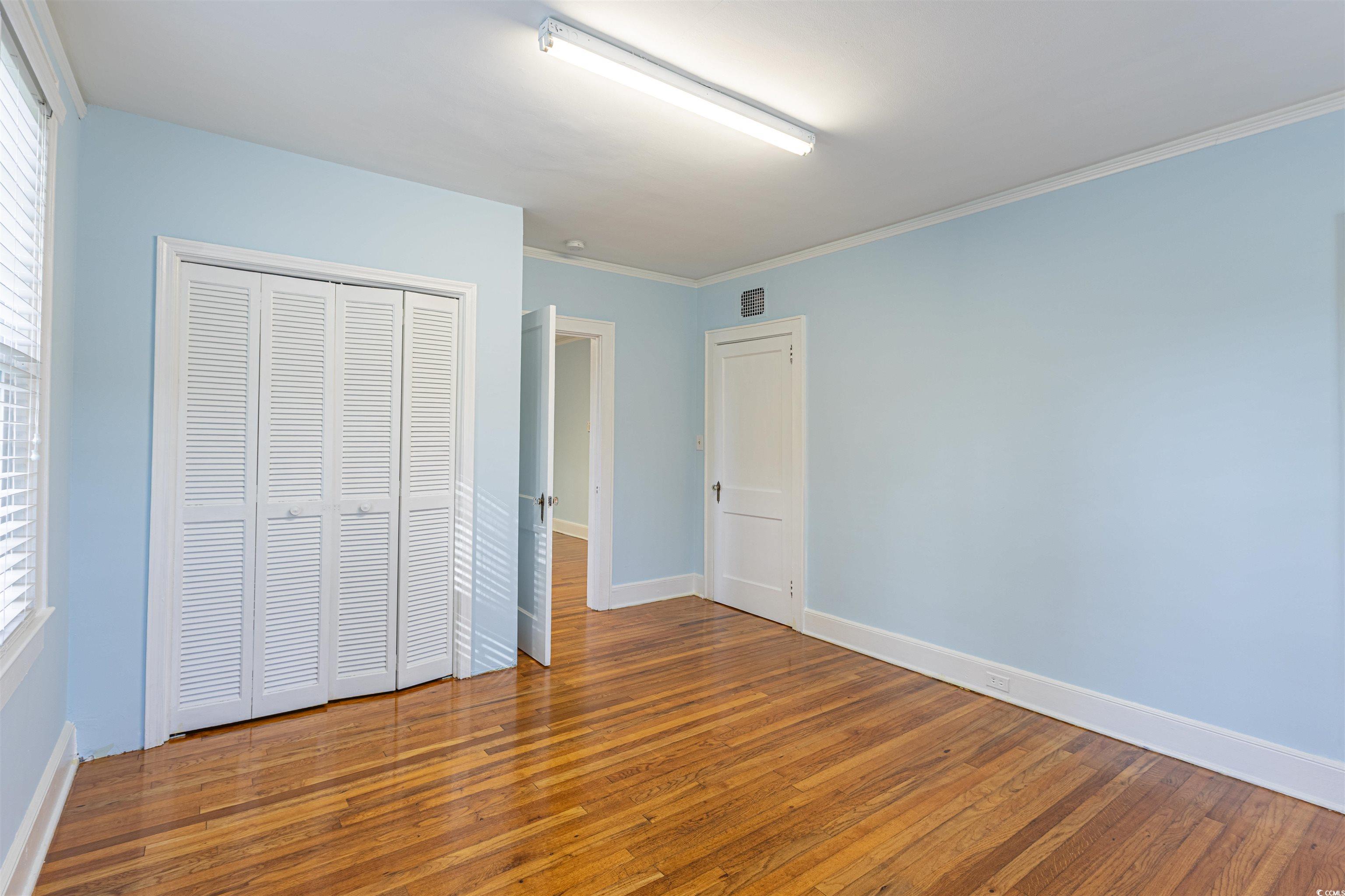505 North Longstreet Street Kingstree, SC 29556 - Photo 21 of 34 Unfurnished bedroom featuring wood-type flooring, a closet, and ornamental molding