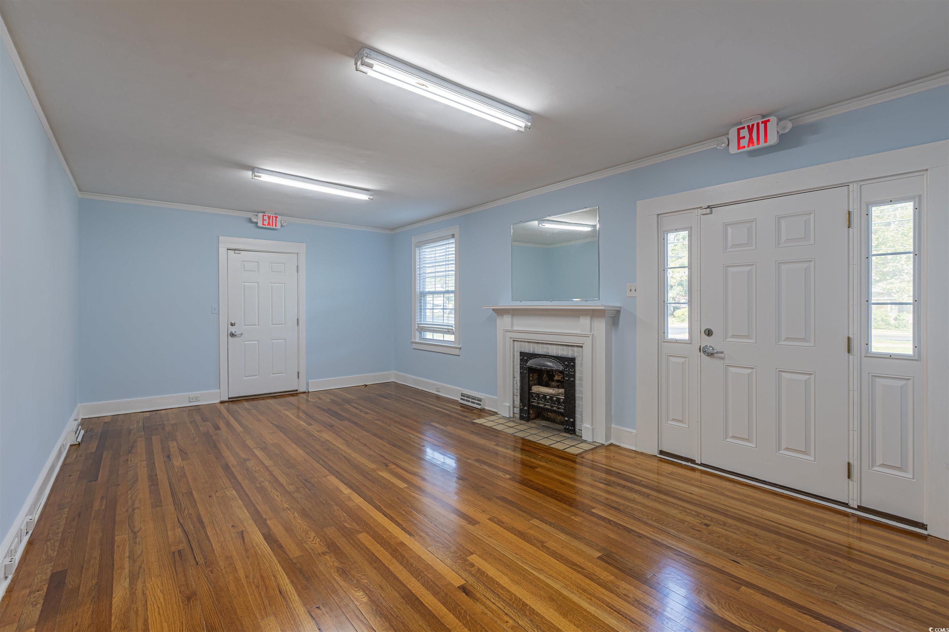 505 North Longstreet Street Kingstree, SC 29556 - Photo 5 of 34 Unfurnished living room featuring crown molding, dark wood-style flooring, and a brick fireplace