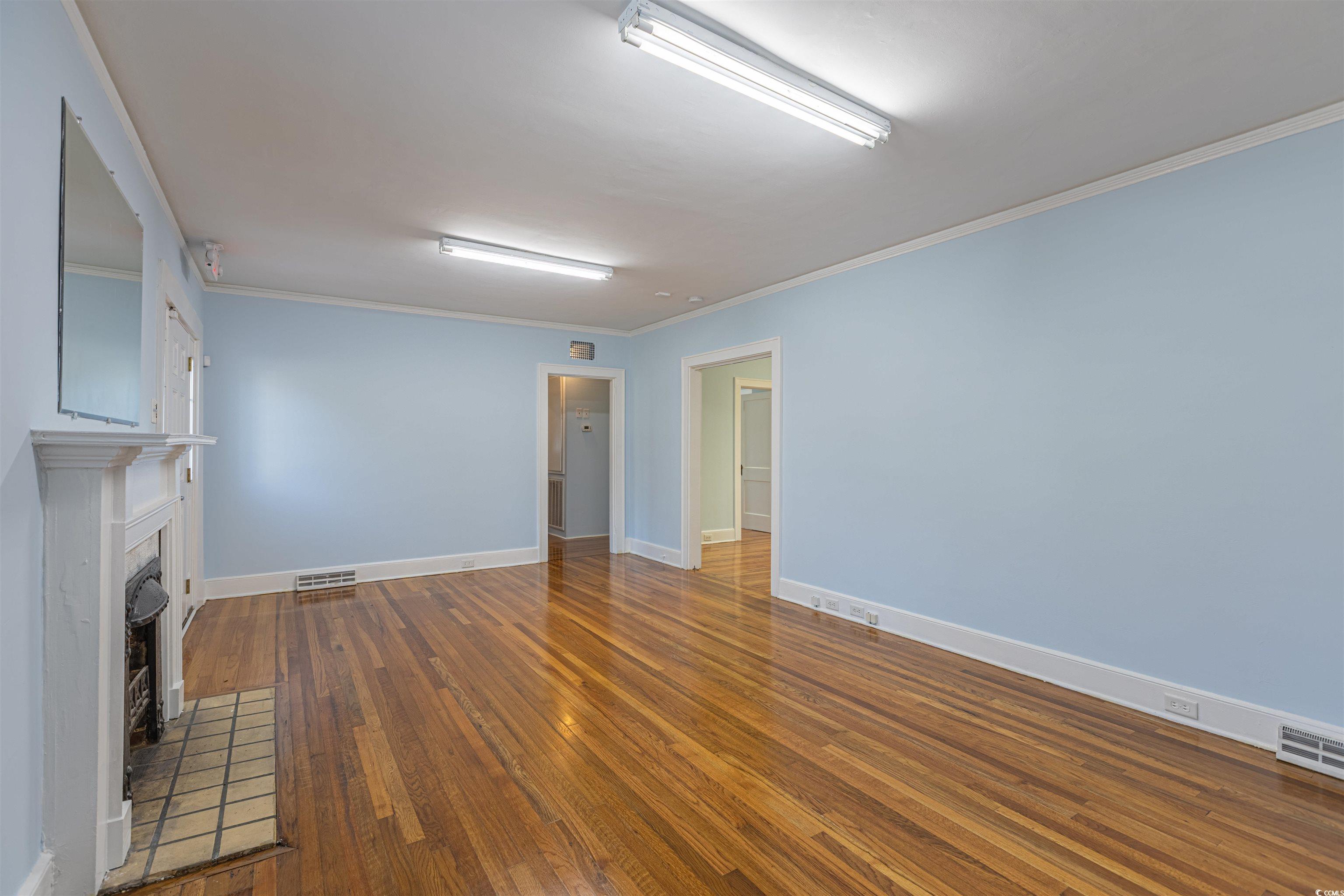 505 North Longstreet Street Kingstree, SC 29556 - Photo 6 of 34 Unfurnished living room with dark wood finished floors, crown molding, and a fireplace