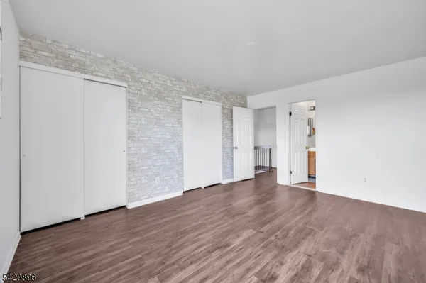 a view of an empty room with wooden floor and closet