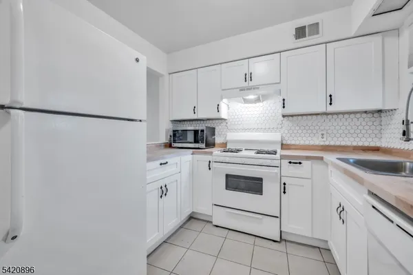 a kitchen with white cabinets and white appliances